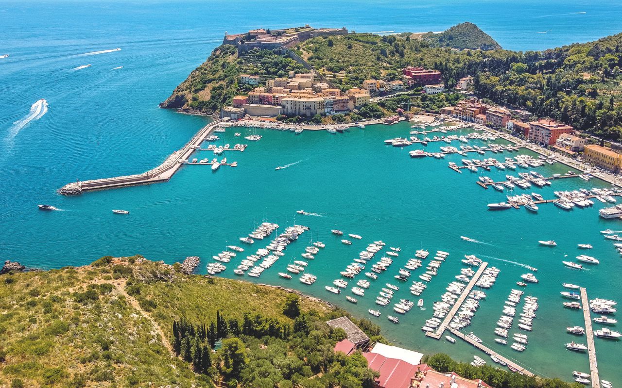 Toscana, i borghi della meraviglia - Porto Ercole espone le sue imbarcazioni in un disegno affascinante, dominato, in alto, dalle fortificazioni spagnole
